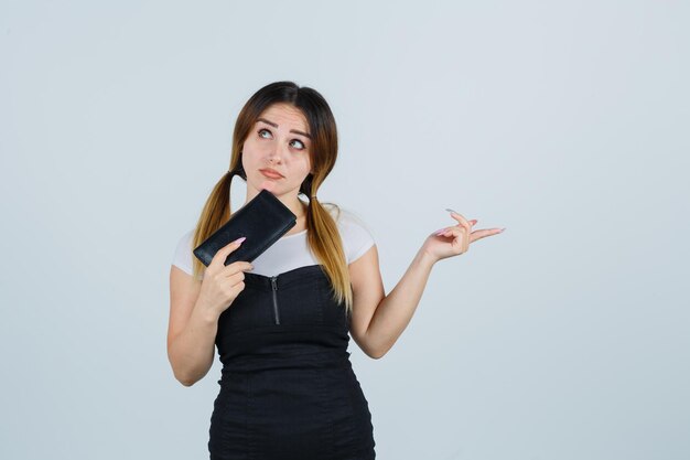 Young woman holding clutch while pointing to the right side