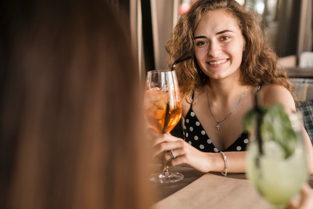 Young woman holding cocktail with her friend