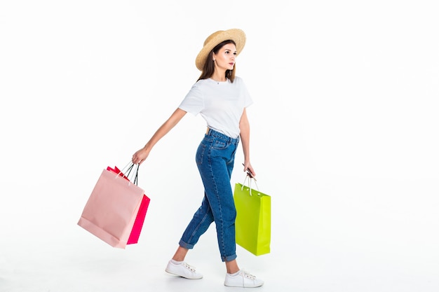 young woman holding colorful bags isolated on white wall
