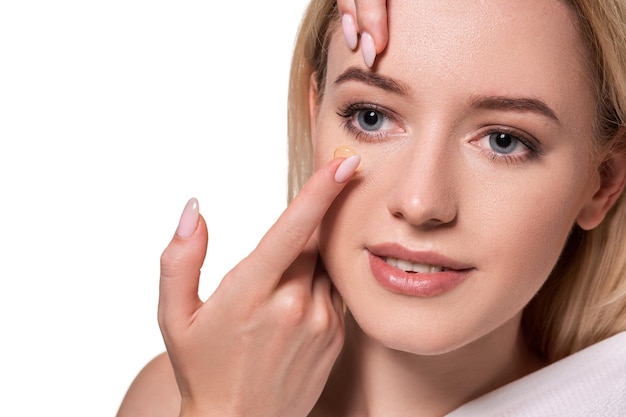 Young woman holding contact lens on index finger with copy space. Close up face of healthy beautiful woman about to wear contact lens. Eyesight and ophthalmology concept.