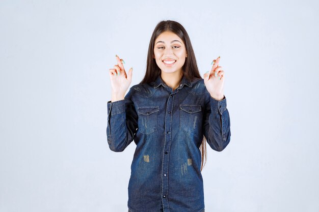 Young woman holding cross sign in the fingers