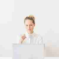 Free photo young woman holding cup of coffee looking at laptop