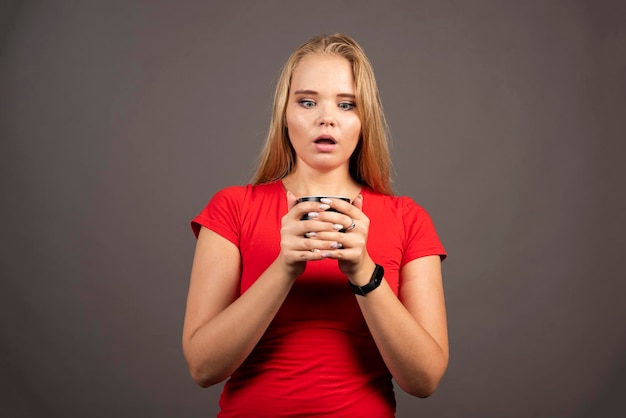 Young woman holding cup of tea on dark background. High quality photo