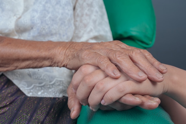 若い女性は高齢者の女性の手を握っています。