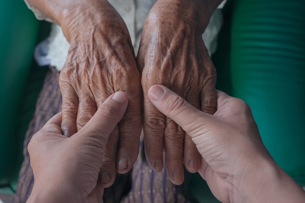 Молодая женщина, держащая руку пожилой женщины.