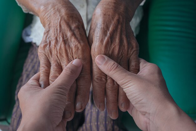 노인 여성의 손을 잡고하는 젊은 여자.