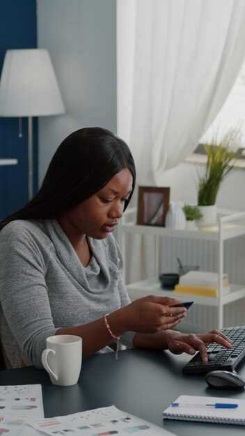 Young woman holding electronic credit card typing online payment on computer keyboard while ordering electronic tablet during online sale