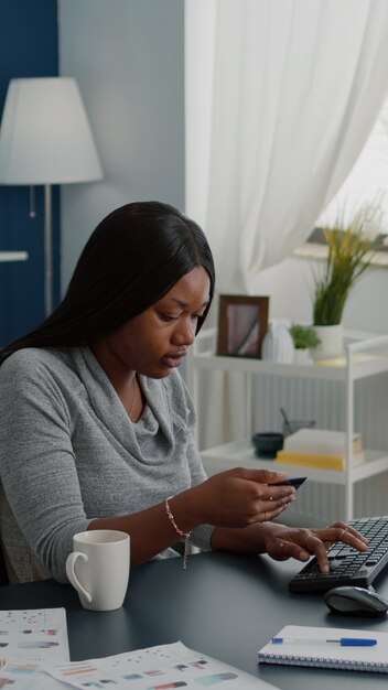 Молодая женщина, держащая электронную кредитную карту, вводит онлайн-платеж на клавиатуре компьютера при заказе электронного планшета во время онлайн-продажи