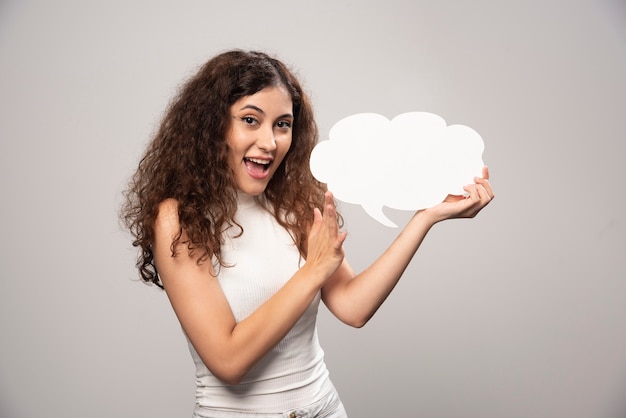 Young woman holding empty blank white speech poster. High quality photo