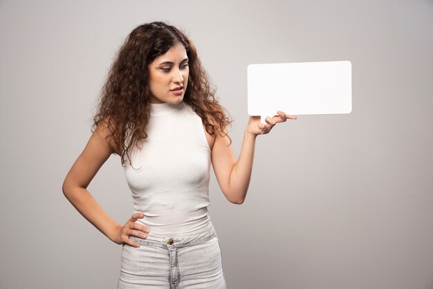 Young woman holding empty blank white speech poster. High quality photo