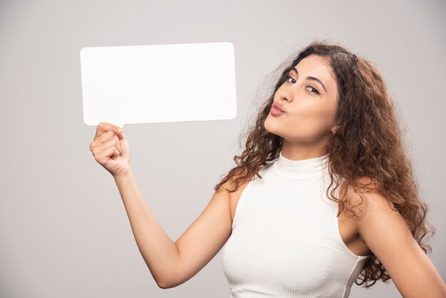 Young woman holding empty blank white speech poster. High quality photo