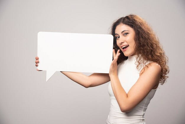 Young woman holding empty blank white speech poster. High quality photo