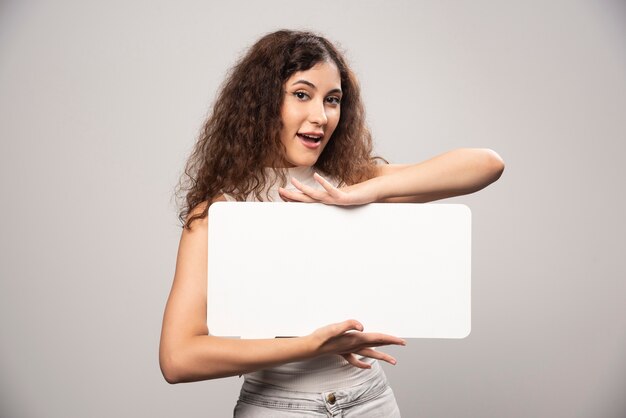 Young woman holding empty blank white speech poster. High quality photo