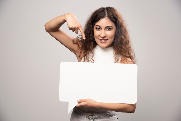 Young woman holding empty blank white speech poster. High quality photo