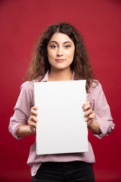 Free photo young woman holding empty canvas.