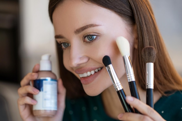 Foto gratuita giovane donna che tiene spazzole per il viso e sorridente