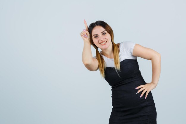 Young woman holding finger over head as horn