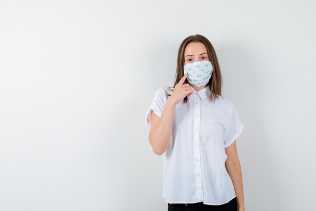 Young woman holding finger on her mask and looking pensive