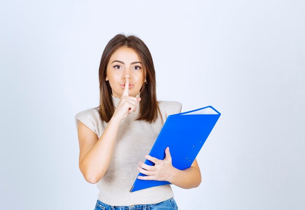 Young woman holding a folder and doing a silent sign .