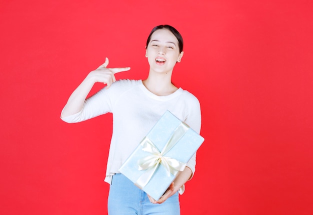 Young woman holding gift box and laughing