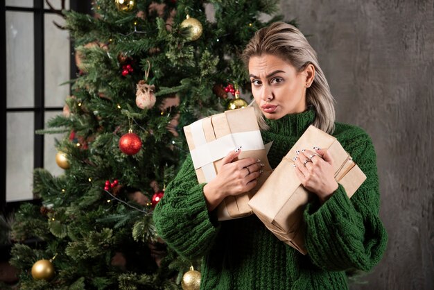 Young woman holding gift box near a Christmas tree