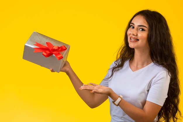 Contenitore di regalo della tenuta della giovane donna con l'arco rosso