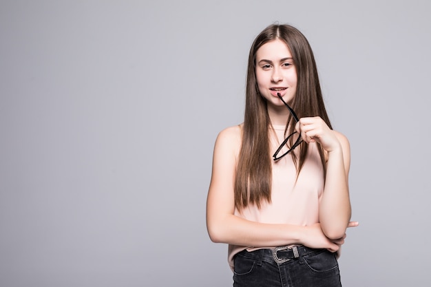 Young woman holding in glasses isolated on gray wall