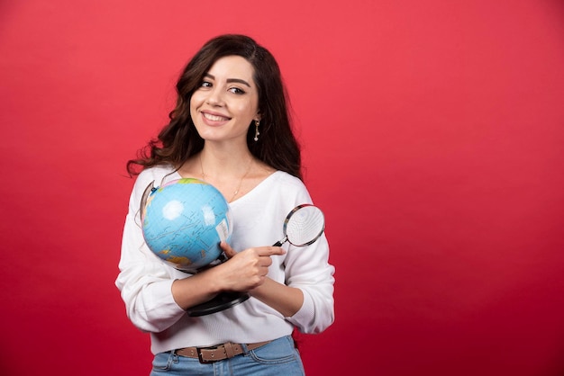 Young woman holding globe and magnifying glass. High quality photo