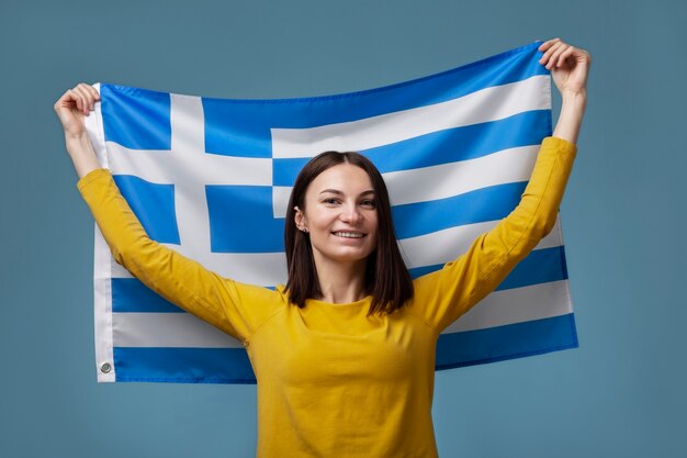 ギリシャの旗を保持している若い女性