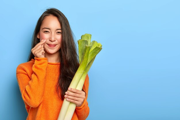 Young woman holding green leeks