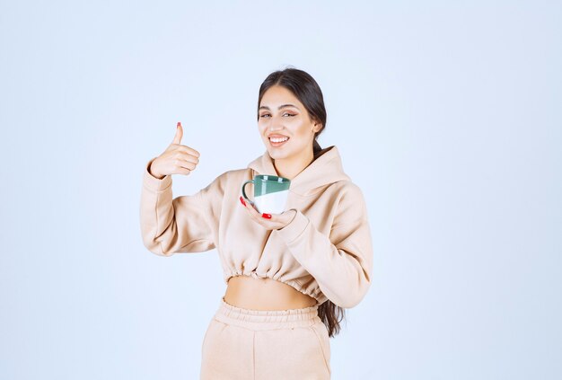 Young woman holding a green mug and showing her satisfaction