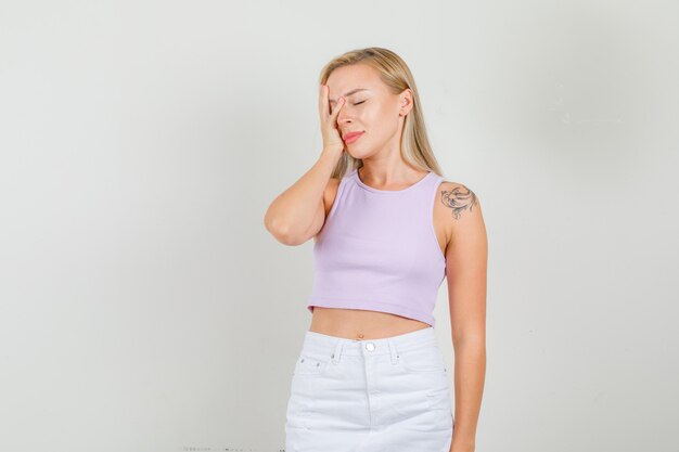 Young woman holding hand on face in singlet