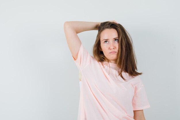 ピンクのTシャツを着て頭に手をつないで躊躇している若い女性。