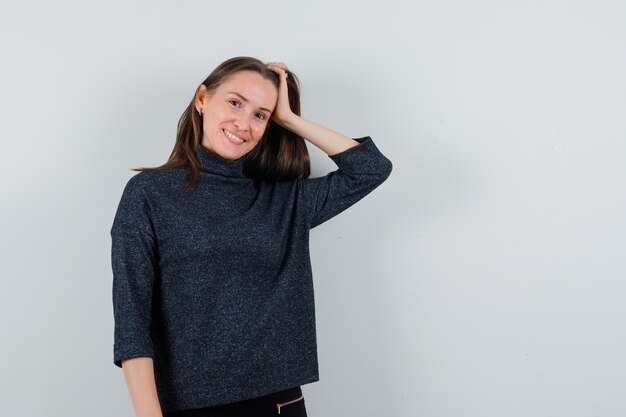 Young woman holding hand on head in shirt and looking cute 