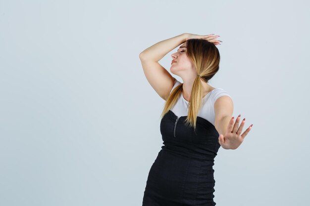 Young woman holding hand on head while showing stop gesture