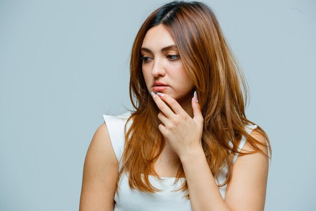 Young woman holding hand on jaw while looking aside