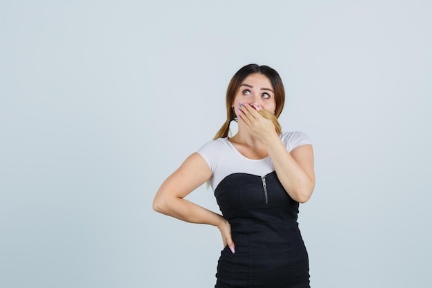 Young woman holding hand on mouth and looking anxious