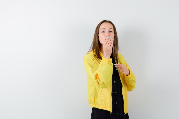 Young woman holding hand over mouth and sending kisses