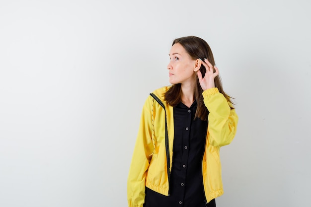 Young woman holding hand near ear to hear something