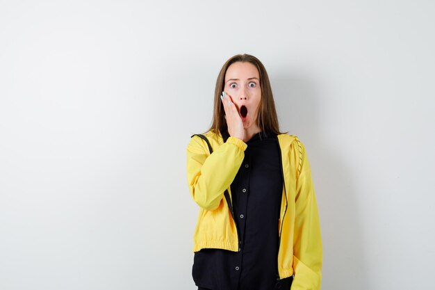 Young woman holding hand near mouth in shock