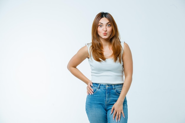 Young woman holding hand on waist while pouting lips