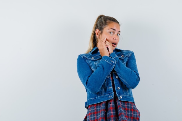 Giovane donna che tiene le mani giunte in camicia, giacca e aspetto delicato. vista frontale.