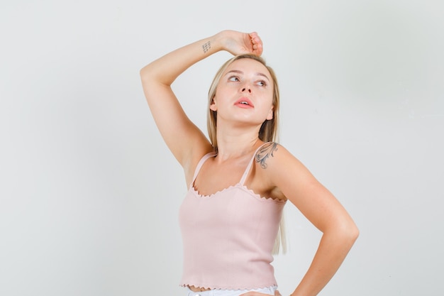 Young woman holding hands on head and waist in singlet