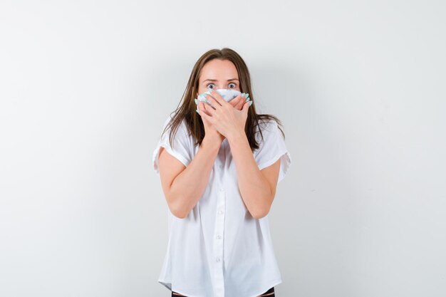 Young woman holding hands on mouth and looking frightened