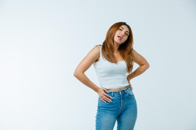 Young woman holding hands on waist while sticking tongue out