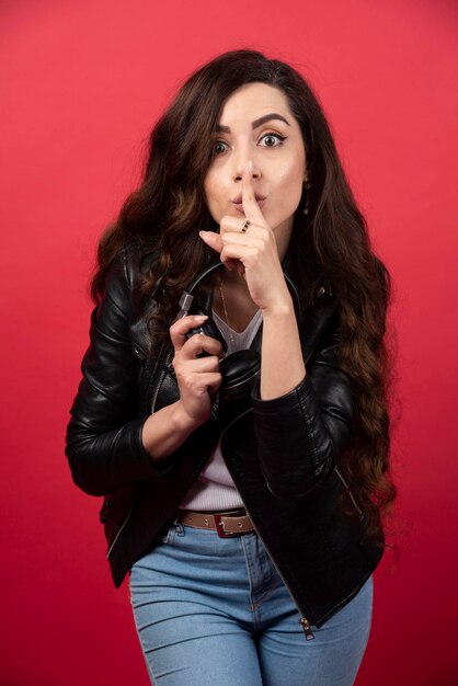 Young woman holding headphones and posing on a red background. High quality photo