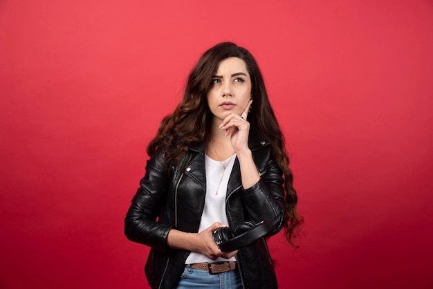 Young woman holding headphones and posing on a red background. High quality photo