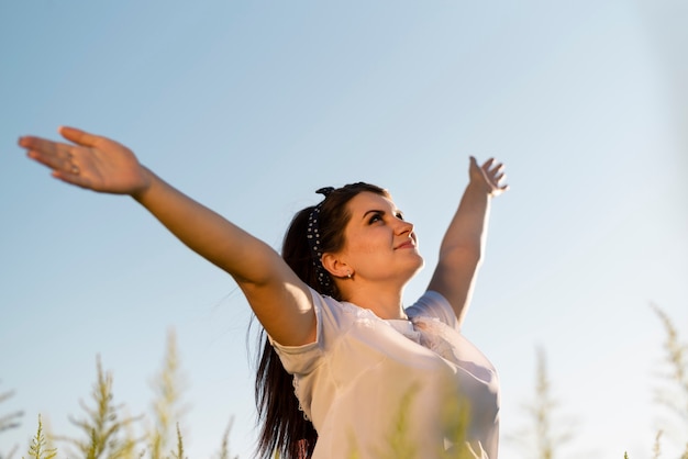 Young woman holding her arms in the air and looking at the sky