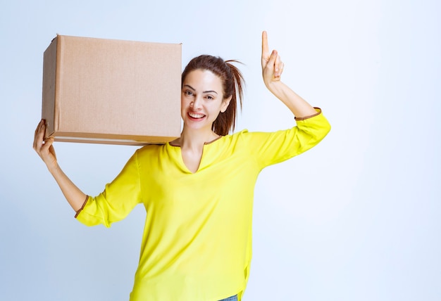 Young woman holding her cardboard parcel and introducing it