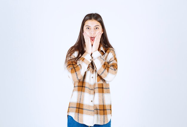 young woman holding her face on white wall. 